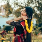 A beautiful young woman poses outdoors in traditional attire, showcasing South Asian aesthetics.