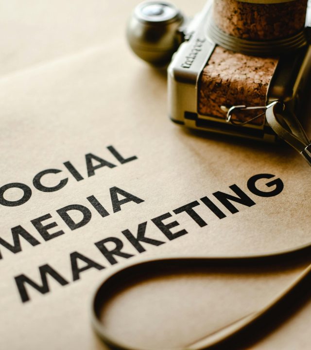Close-up of a camera placed on brown paper with 'Social Media Marketing' text, emphasizing digital marketing themes.