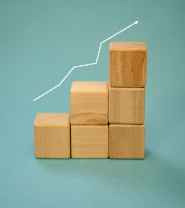Wooden blocks forming a staircase with an upward arrow symbolizing growth and progress.